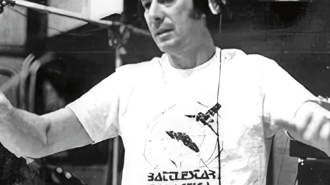 A shot of composer Stu Phillips conducting while wearing a Battlestar Galactiva t-shirt.